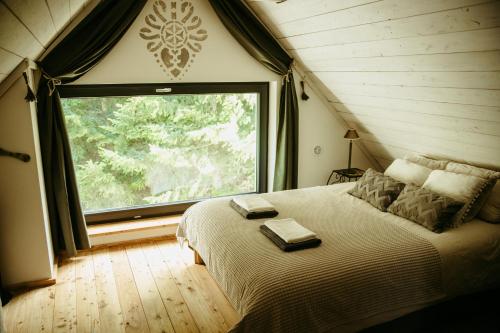 une chambre avec un lit avec une grande fenêtre dans l'établissement Szumidomki strefa z jacuzzi sauna widok na potok las, à Zawoja