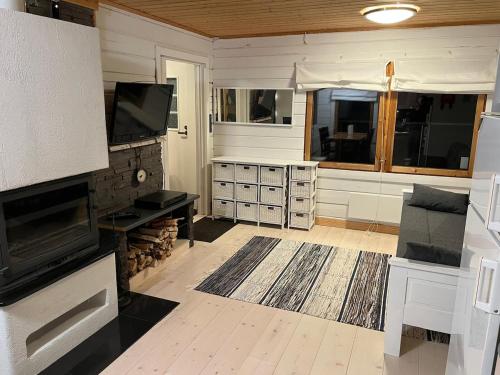 a living room with a fireplace and a tv at Cottage on the shore of Ivalojoki in Inari