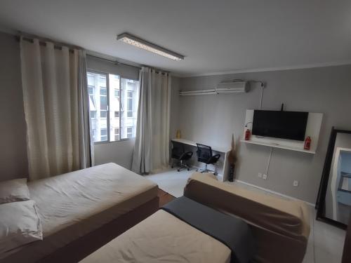 a hotel room with two beds and a flat screen tv at Apto Studio 202 centro floripa in Florianópolis