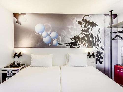 a room with a bed with a painting of a cowboy at Ibis Styles Paris Saint Denis La Plaine in Saint-Denis