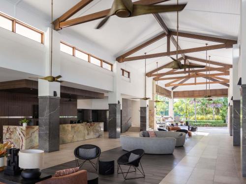 una sala de estar de planta abierta con sofás y sillas. en Pullman Port Douglas Sea Temple Resort and Spa, en Port Douglas