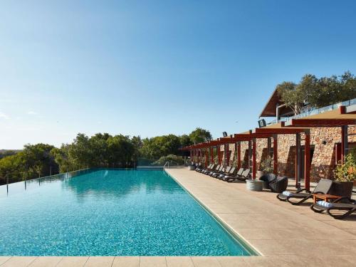 a swimming pool with lounge chairs next to a building at Pullman Bunker Bay Resort Margaret River in Dunsborough
