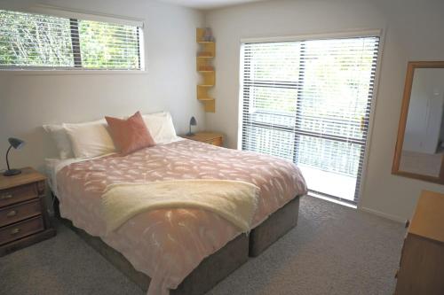 une chambre avec un grand lit et deux fenêtres dans l'établissement House close to Oneroa Village, beach, and wineries, à Waiheke Island