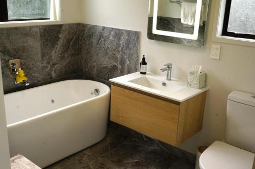 une salle de bain avec une baignoire, un lavabo et des toilettes dans l'établissement House close to Oneroa Village, beach, and wineries, à Waiheke Island