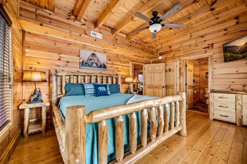 Un dormitorio tipo cabaña de madera con una cama y un ventilador de techo. en Fall Family Fun-Pool in Cabin-View-Games-Hot Tub, en Sevierville
