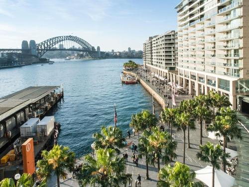 a view of a river with a bridge and buildings at Pullman Quay Grand Sydney Harbour in Sydney