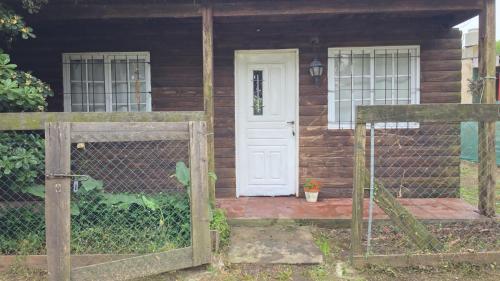 a wooden house with a white door and a fence at Hospedaje La Cabaña in San Miguel del Monte