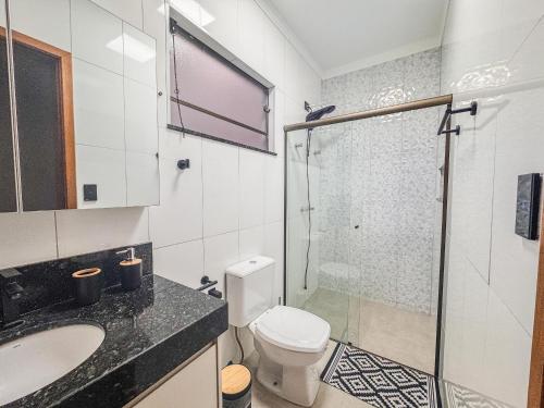 a bathroom with a shower and a toilet and a sink at Casa em bairro nobre + 3 quartos com ar e 2 vagas in Ourinhos