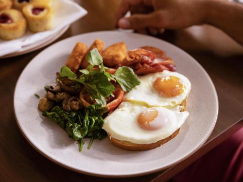 a plate of food with eggs and vegetables on a table at Novotel Sydney Parramatta in Sydney
