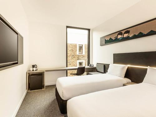 a hotel room with two beds and a flat screen tv at ibis Adelaide in Adelaide
