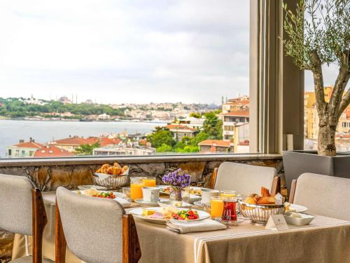 een tafel met eten en uitzicht op het water bij The Artisan Hotel Istanbul - MGallery Collection in Istanbul