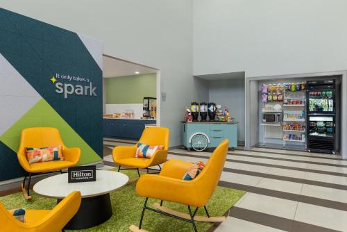a waiting room at a spartan supermarket with orange chairs at Spark by Hilton Indianapolis Northeast Fishers in Fishers
