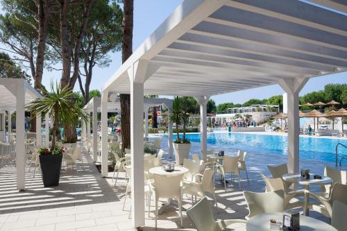 a patio with tables and chairs next to a pool at Ca' Pasquali Village in Cavallino-Treporti