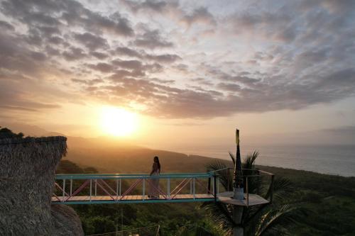 a woman walking on a bridge with the sunset in the background at Puerto Alto Hostel in Santa Marta
