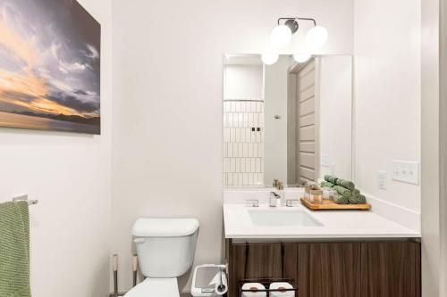 a bathroom with a sink and a toilet and a mirror at Midtown Luxury with Skyline Views in Atlanta