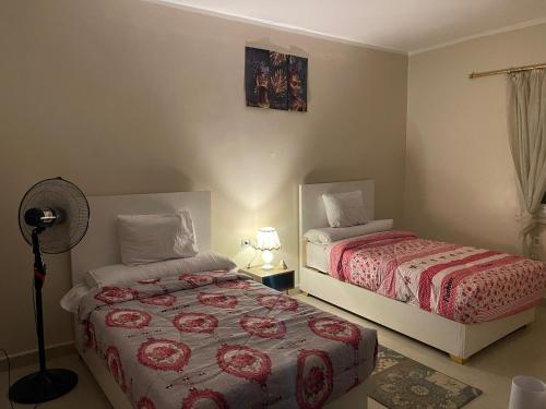 Un dormitorio con dos camas y un ventilador. en ABAr, en Banī Ghālib