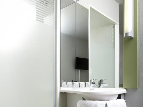 a bathroom with a sink and a mirror at ibis budget Pontarlier in Pontarlier