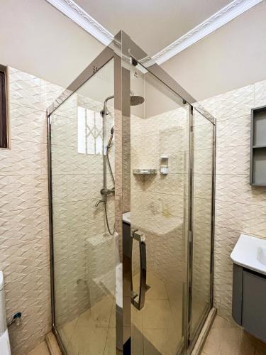 a shower with a glass door in a bathroom at Palms & Pebbles Home in Lilongwe