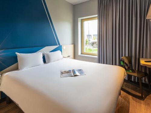 a hotel room with a bed with a magazine on it at ibis budget Epinal in Épinal