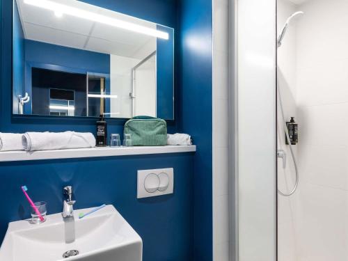 a blue bathroom with a sink and a mirror at ibis budget Epinal in Épinal