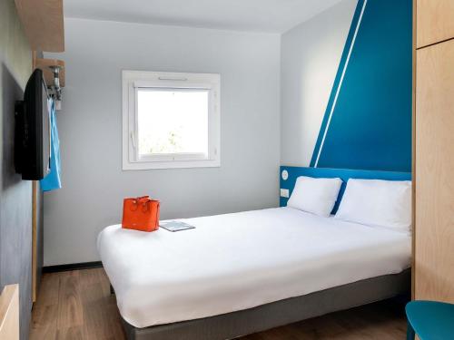 - une chambre dotée d'un grand lit avec un sac orange dans l'établissement Hotel Ibis Budget Fecamp, à Fécamp