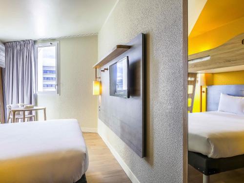 a hotel room with two beds and a tv at ibis budget Fontainebleau Avon in Avon