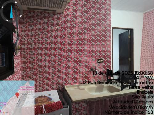 a red tiled bathroom with a sink and a mirror at Chalé da Elba in Ilhabela