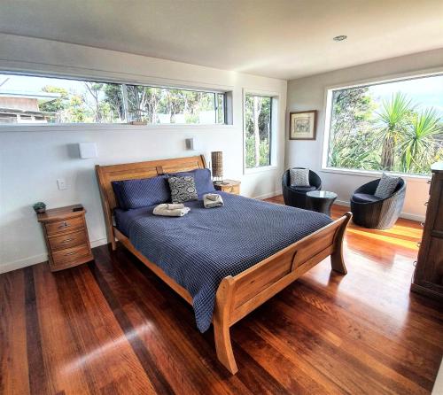 a bedroom with a large bed and two chairs at XSPOT Cliff House apartment, secluded 4WD location in Great Barrier Island