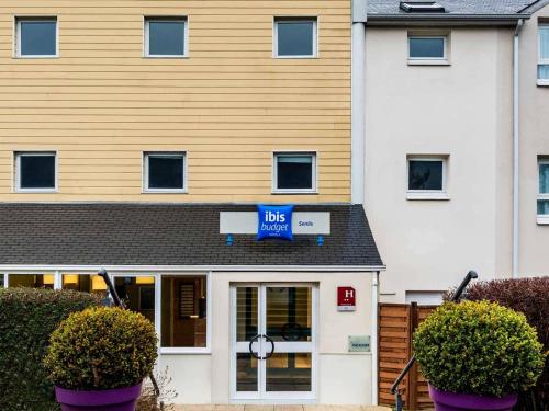 a large white building with a blue sign on it at ibis budget Senlis in Senlis