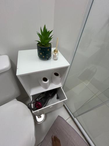 a white side table with a plant on it in a bathroom at Apto Itaipava 5 min do Centro e Parque de Eventos in Itaipava