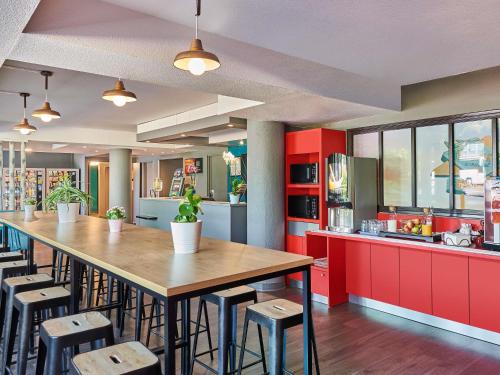 a kitchen with red cabinets and a long table at hotelF1 Roissy CDG Pn2 in Roissy-en-France