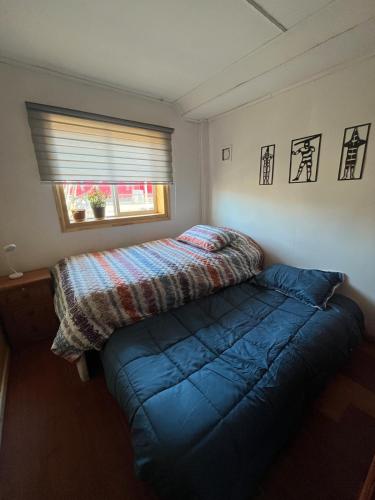 a small bedroom with a bed and a window at Cabaña en Cochrane in Cochrane
