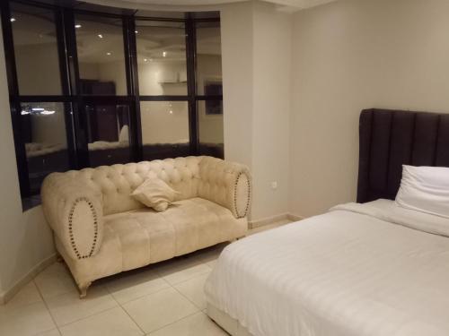 a white couch sitting in a bedroom next to a bed at النخيل للشقق الفندقية in Jeddah