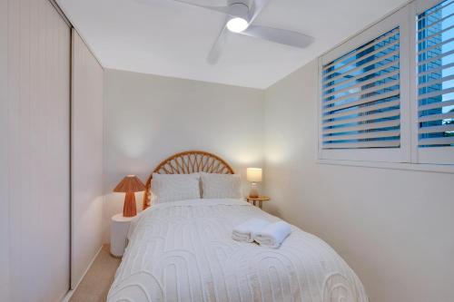 a bedroom with a white bed with two towels on it at Freshly Renovated Oceanfront Bliss Walk to Surf & Dining in Alexandra Headland