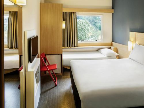 a hotel room with two beds and a tv at ibis Juiz de Fora in Juiz de Fora