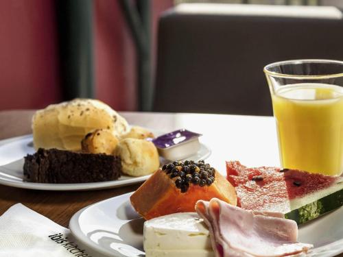 a plate of food on a table with a glass of orange juice at ibis Juiz de Fora in Juiz de Fora