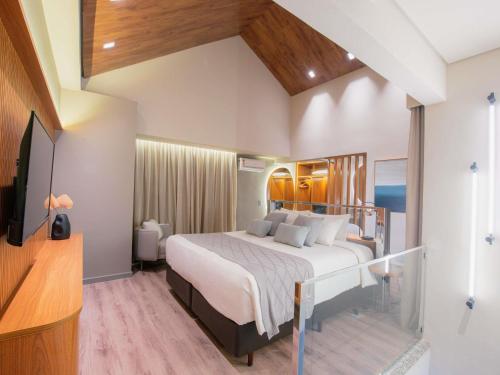 a bedroom with a large bed and a television at Mercure Curitiba Batel in Curitiba