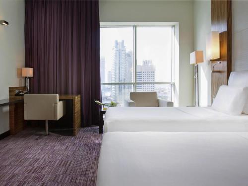 a hotel room with two beds and a large window at Pullman Dubai Jumeirah Lakes Towers in Dubai