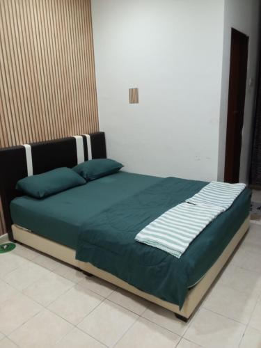 Bett mit grüner Decke in einem Schlafzimmer in der Unterkunft ISLAMIC HOMESTAY CASA NAUFAL FULLY AIRCOND for 1LR 3BR in Port Dickson