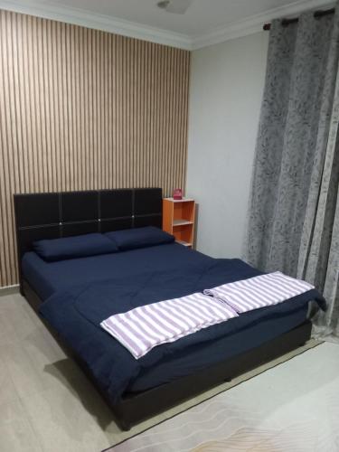 a bedroom with a bed with a blue comforter at ISLAMIC HOMESTAY CASA NAUFAL FULLY AIRCOND for 1LR 3BR in Port Dickson