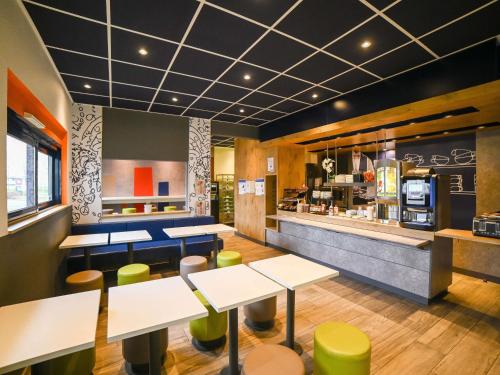 um restaurante com mesas e cadeiras e um balcão em ibis budget Poitiers Site du Futuroscope em Chasseneuil-du-Poitou