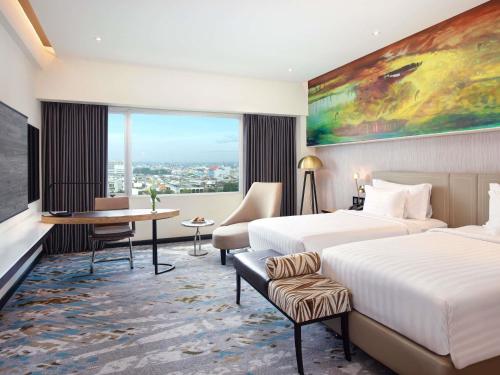 a hotel room with two beds and a large window at Grand Mercure Medan Angkasa in Medan