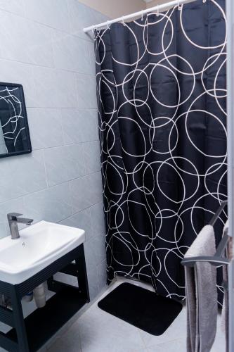 a bathroom with a black shower curtain and a sink at Palms & Pebbles Lodge in Lilongwe