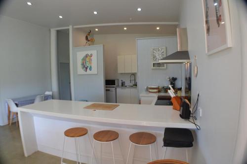 una cucina con bancone bianco e sgabelli di Magical property close to Mangawhai a Mangawhai