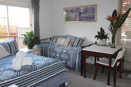 a living room with a bed and a desk with a table at Byron Bay Nest Homestay in Byron Bay