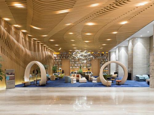 a library with couches and chairs and bookshelves at NOVOTEL Jinji Lake Suzhou SIP in Suzhou