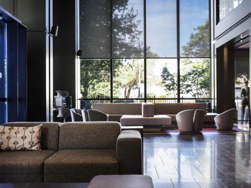 sala de estar con sofá, sillas y ventanas grandes en Pullman Sydney Airport, en Sídney
