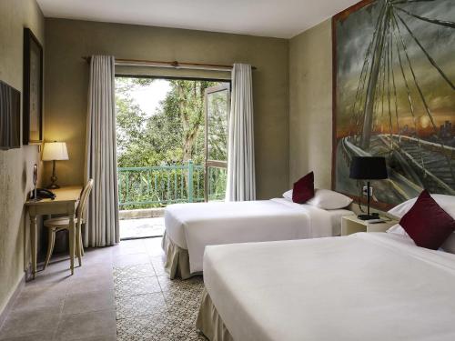 a hotel room with two beds and a window at Mercure Danang French Village Bana Hills in Da Nang