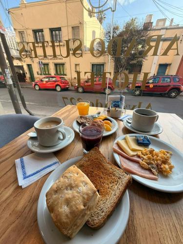 a wooden table with plates of food and cups of coffee at Hotel Alvarado Suites in Salta