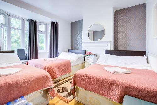 a bedroom with two beds and a mirror at Twin Towers Hotel in London